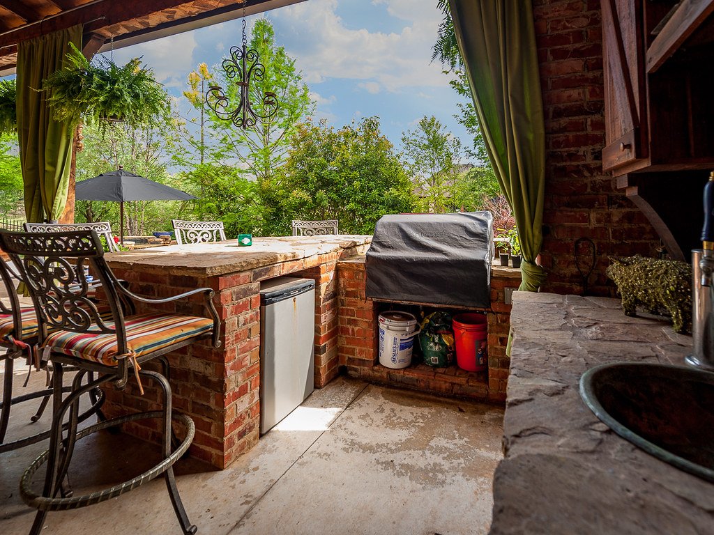 A stone fire pit surrounded by patio seating in a backyard