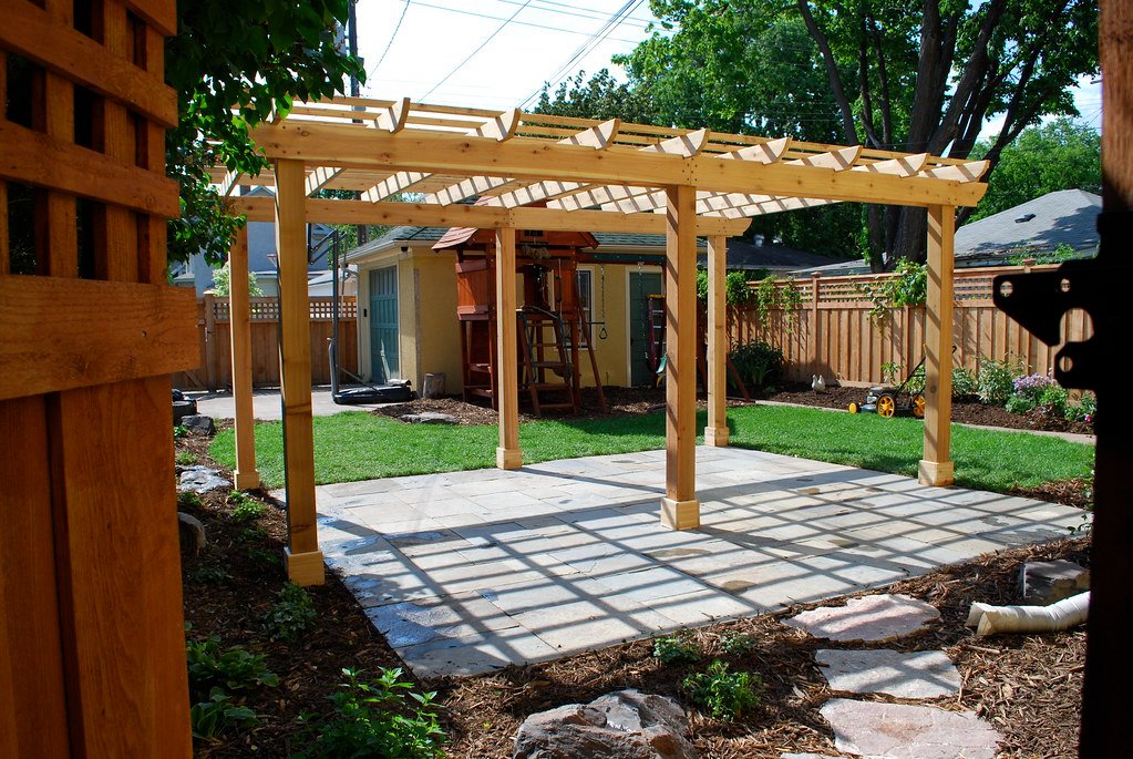 A timber pergola built over a bluestone patio in a residential backyard